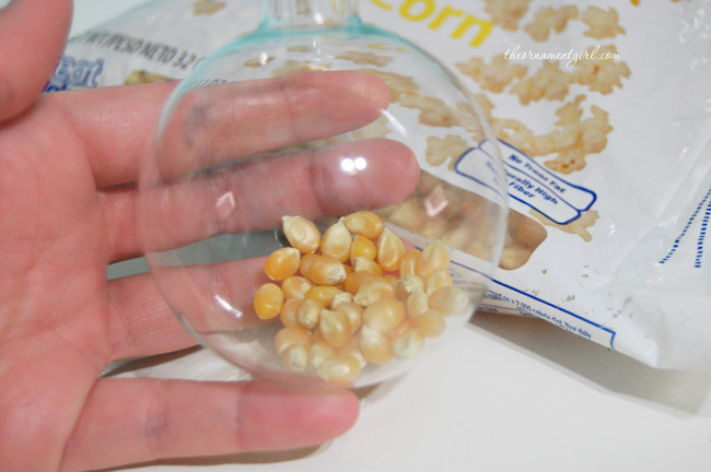 fill clear glass ornament with popcorn kernels
